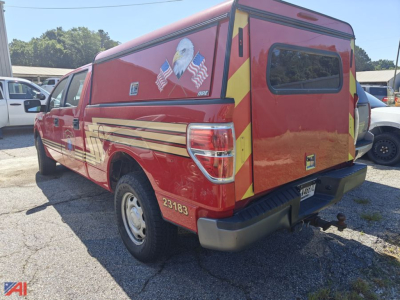 2013 Ford F-150 emergency pickup truck with cap, red crew cab with back storage capsule, decals, and bumper hitch.