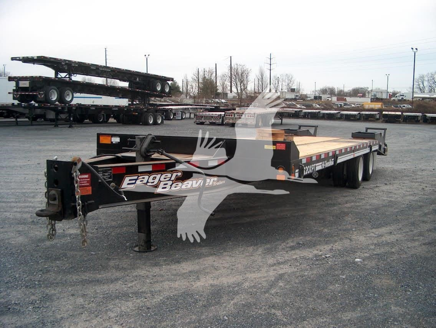 Trailer in a lot showing a flatbed with ramp and branding reading Eager Beaver