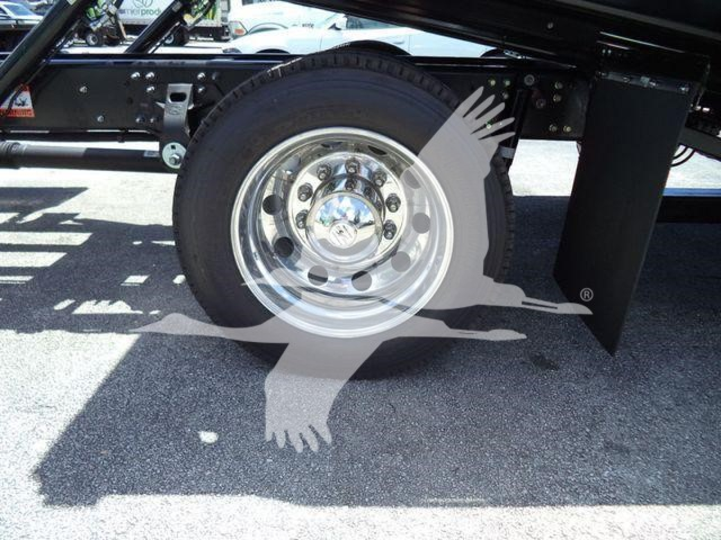 Trucks undercarriage showing rear wheel and suspension with chrome wheel and black frame.