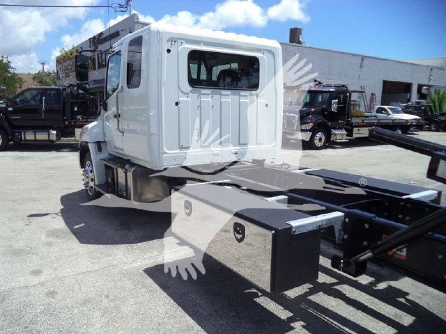 New 2026 Hino L6 rollback truck cab and chassis with flatbed frame and storage boxes visible.