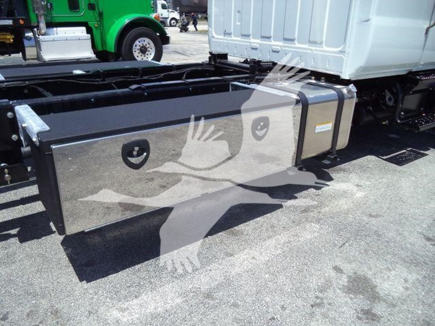 Hino L6 rollback truck chassis with long rectangular aluminum toolbox on side, mounted under cab, with straps and mounting brackets visible.