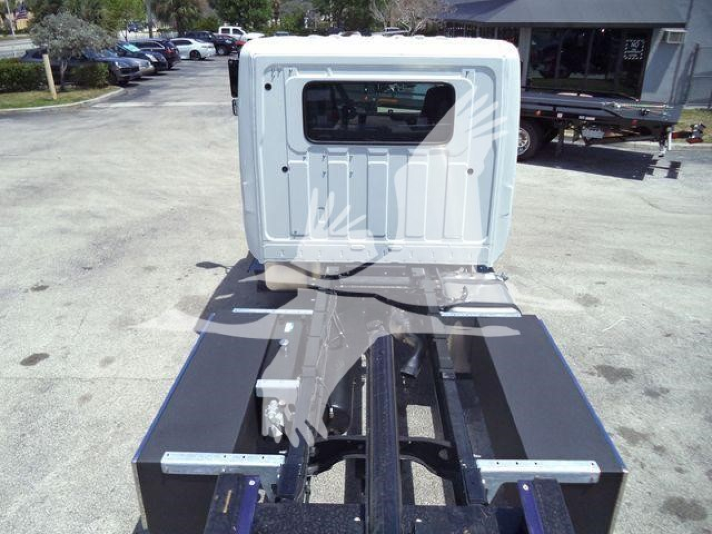 Truck cab and chassis frame in a rollback preparation showing the rear cab area and metal frame rails.