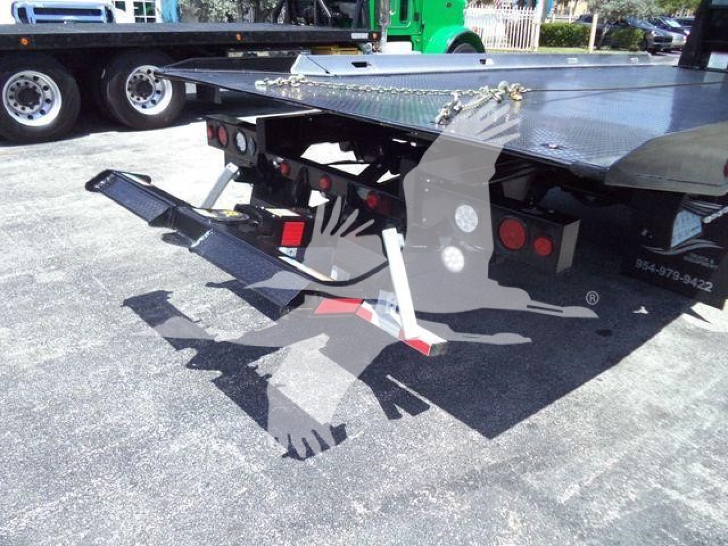 Hino rollback truck platform with hydraulic ramps and rear underlift, visible labels and components under the bed.
