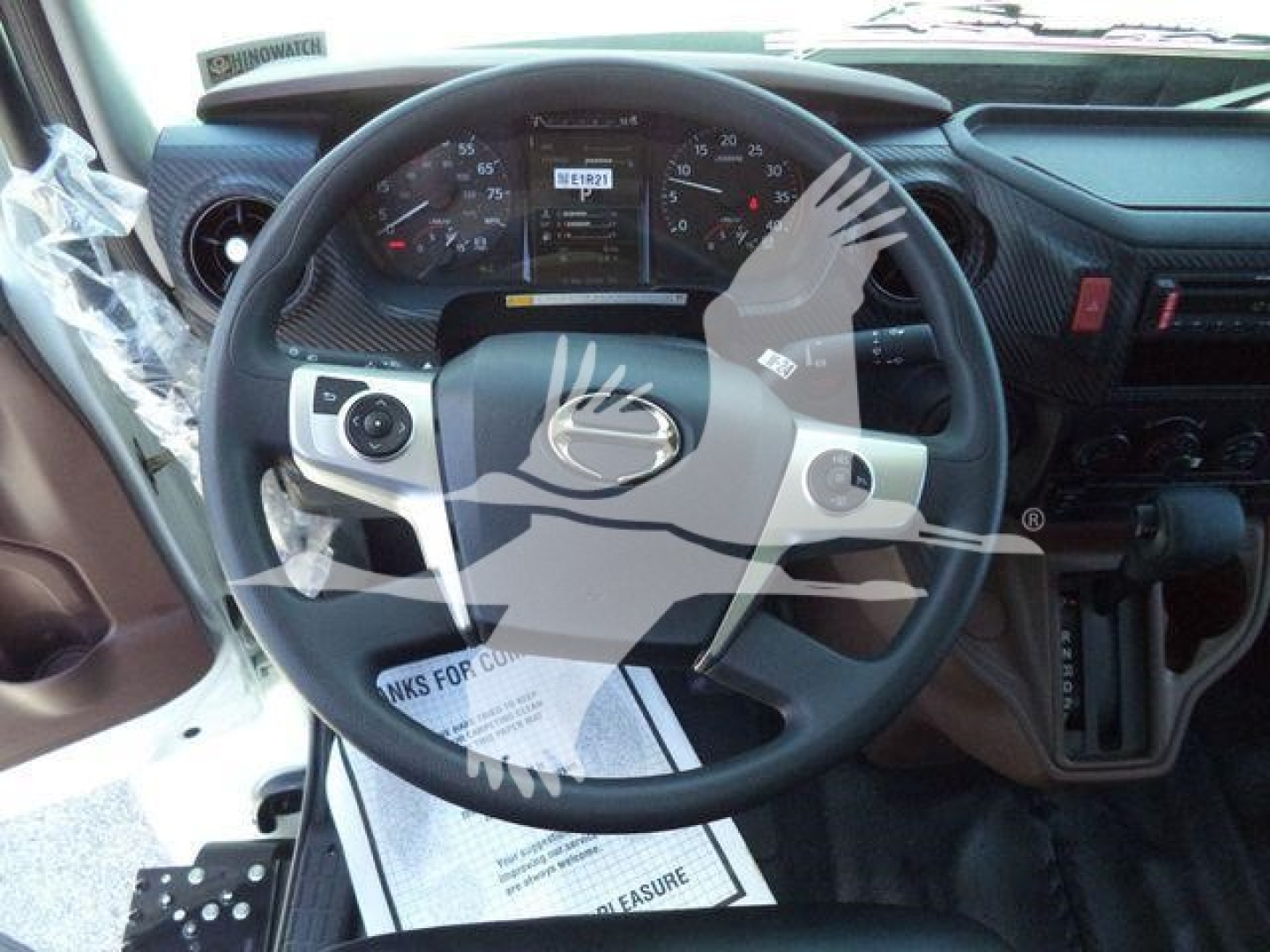 Steering wheel and dashboard of a Hino L6 truck cab in view showing gauges and controls