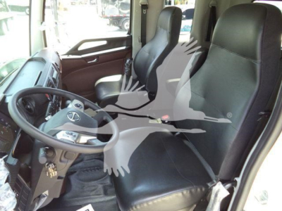 Inside cab of a 2026 Hino L6 truck showing black leather seats, steering wheel, dashboard and driver-side door with controls.