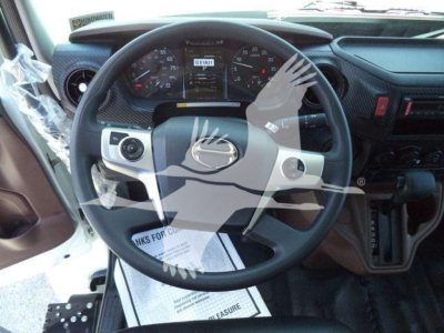 Steering wheel and dashboard of a Hino L6 truck cab in view showing gauges and controls