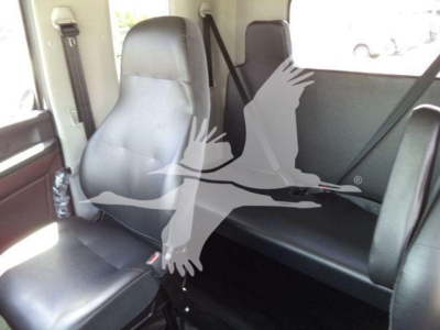 Truck interior showing front seat and rear bench seat in a compact cab with black upholstery; seat belts visible.
