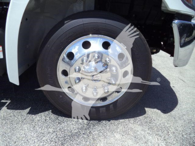 Wheel and tire close-up on a Hino truck front, chrome hubcap with multiple bolts and tire tread visible.