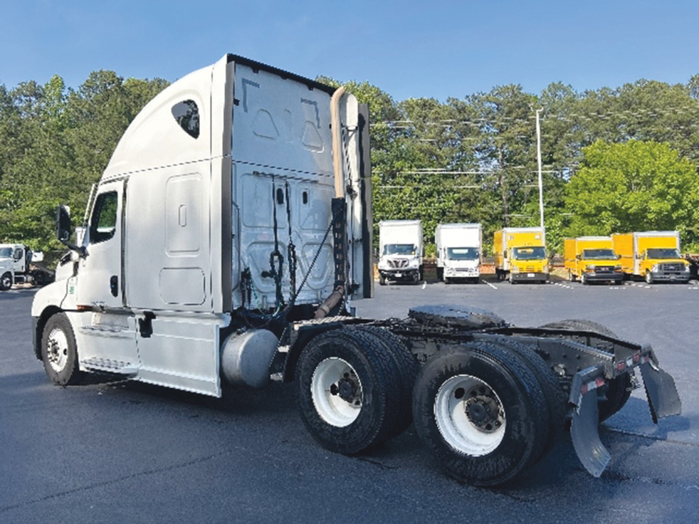 Truck chassis and cab of a used 2022 Freightliner Cascadia126 sleeper with dual rear axles, side view showing VIN and stock info in a dealership lot.