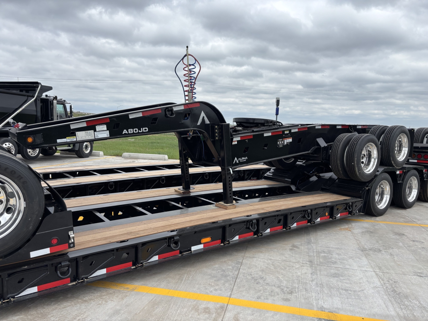 Trailer show with multiple axles and a gooseneck hitch; visible labeling reads A80JD and Alpha branding on the trailer.