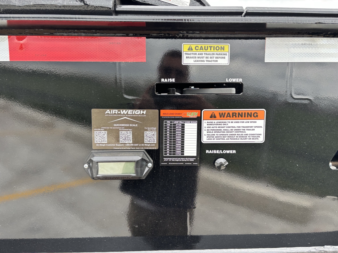 Back of a trailer hitch assembly with air-weigh scale and warning labels, including CAUTION and WARNING stickers, raise/lower lever, and digital display.