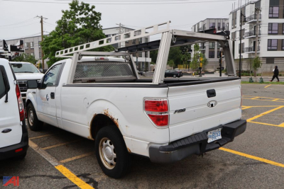 Ford F-150 pickup truck with utility ladder rack and bed cap, white, 2010 model, rear three-quarter view showing tailgate and hitch