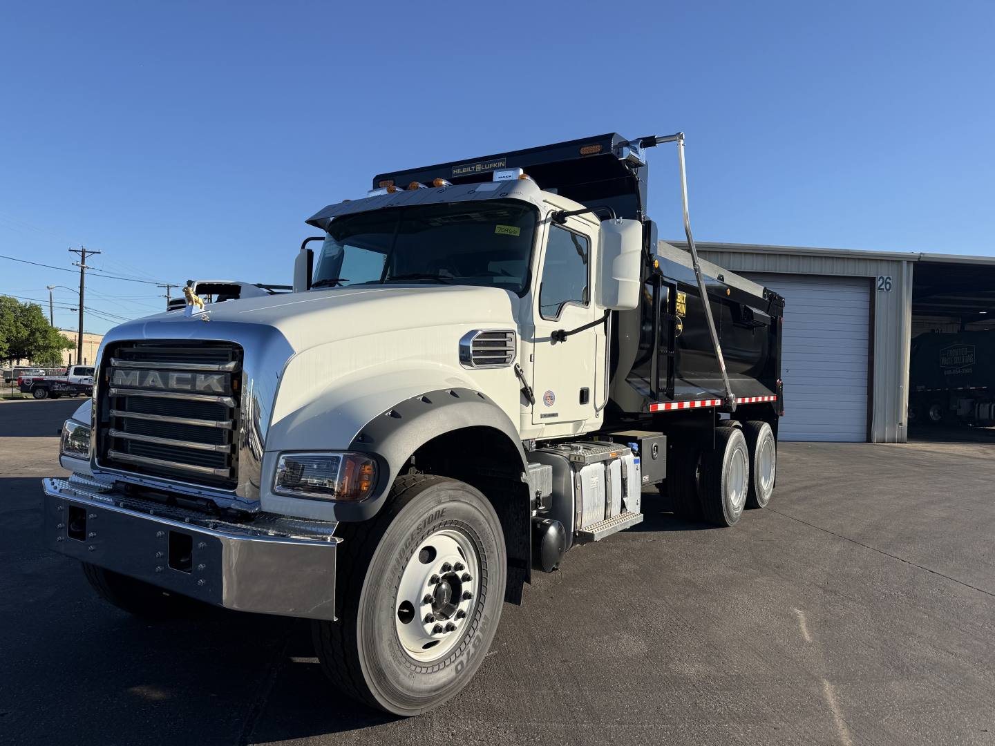 Mack GR64F dump truck in pristine condition shown from front-left angle with dump body and dual rear axles.
