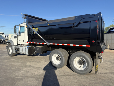 Dump truck with black dump body and white cab showing Mack GR64F, side view, with text on decals and ladder.