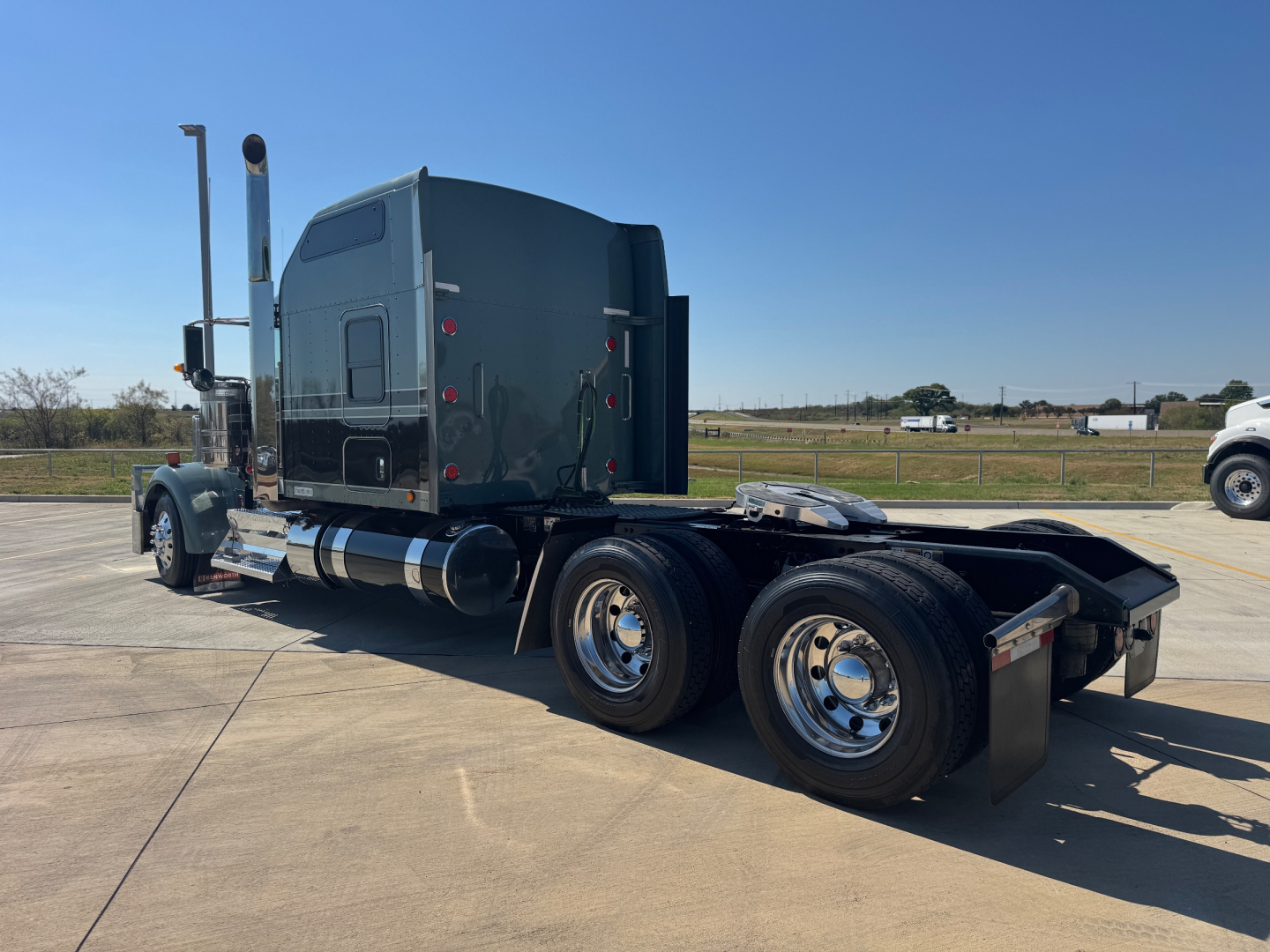 Kenworth W900L tractor shown in side profile with dual rear axles and sleeper cab; chrome fuel tanks; text not clearly visible on cab panels.