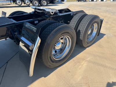 Kenworth W900L rear dual axle tractor chassis showing tandem wheels, chrome rims, and fender, with fifth wheel hitch area visible.