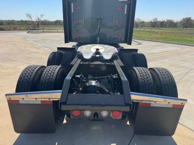 Rear view of a Kenworth W900L tractor chassis showing fifth wheel, dual rear axles, mud flaps, and deck with connector panels; the cab is not visible.