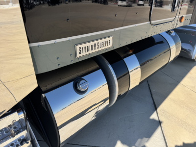 Kenworth W900L side view showing polished chrome fuel tanks and 'STUDIO SLEEPER' plate on side panel.