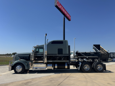 Kenworth W900L conventional sleeper semi-truck with a chrome-detailed cab and a dump trailer attached, side view.