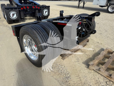 Fontaine flip axle trailer showing dual wheels, hydraulic lines, and control components with front hitch area and spare pallets nearby.
