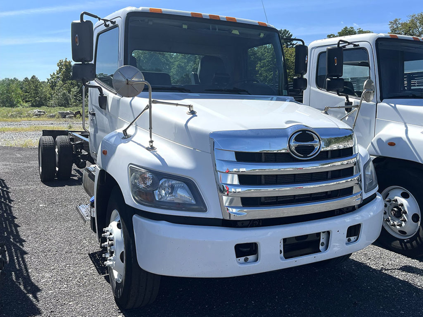 Front view of a white 2019 Hino 338 cab and chassis truck with chrome grille, dual mirrors, and large headlights.