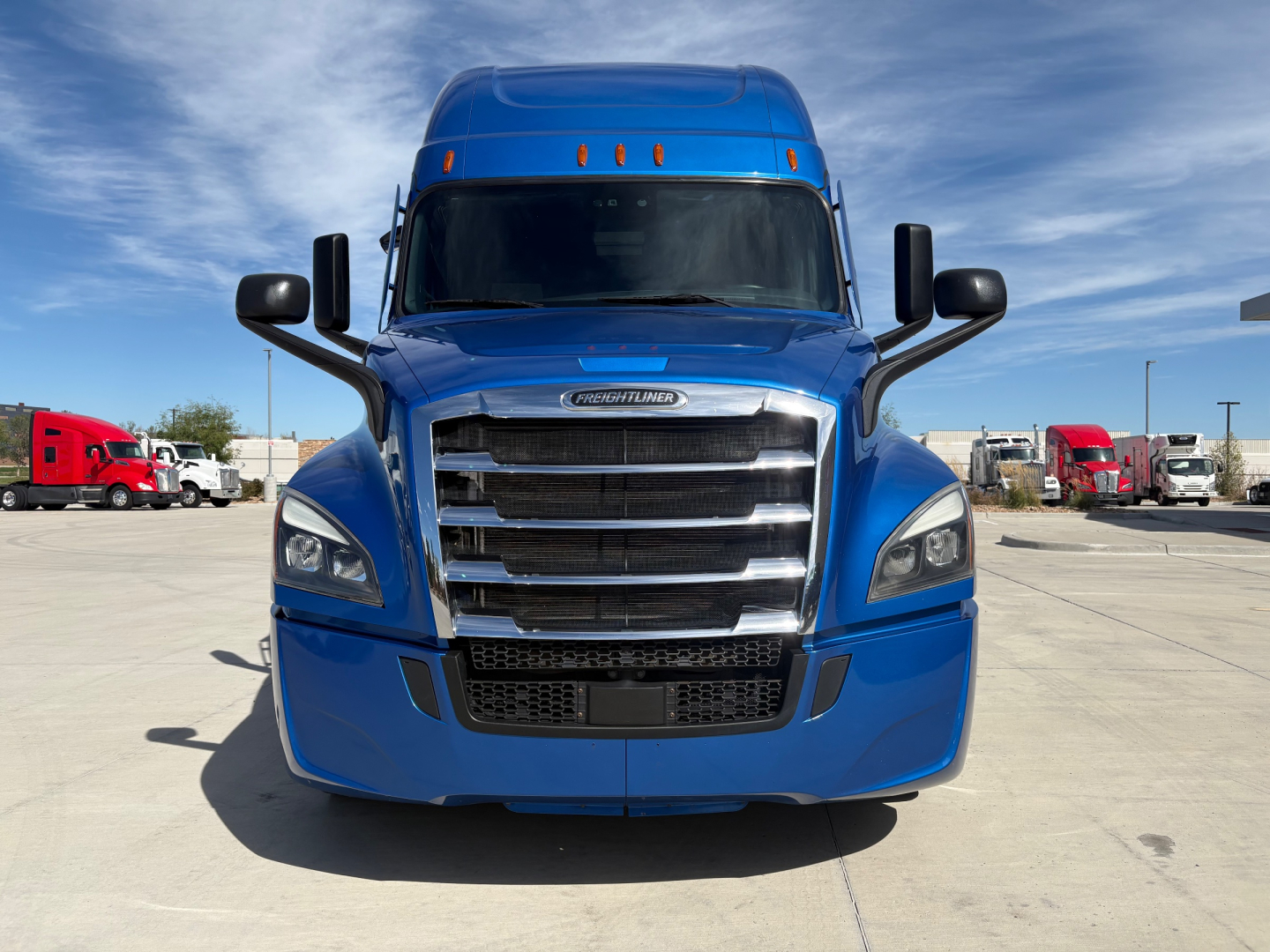Freightliner conventional sleeper truck front view showing blue cab, prominent grille, headlights, and side mirrors.