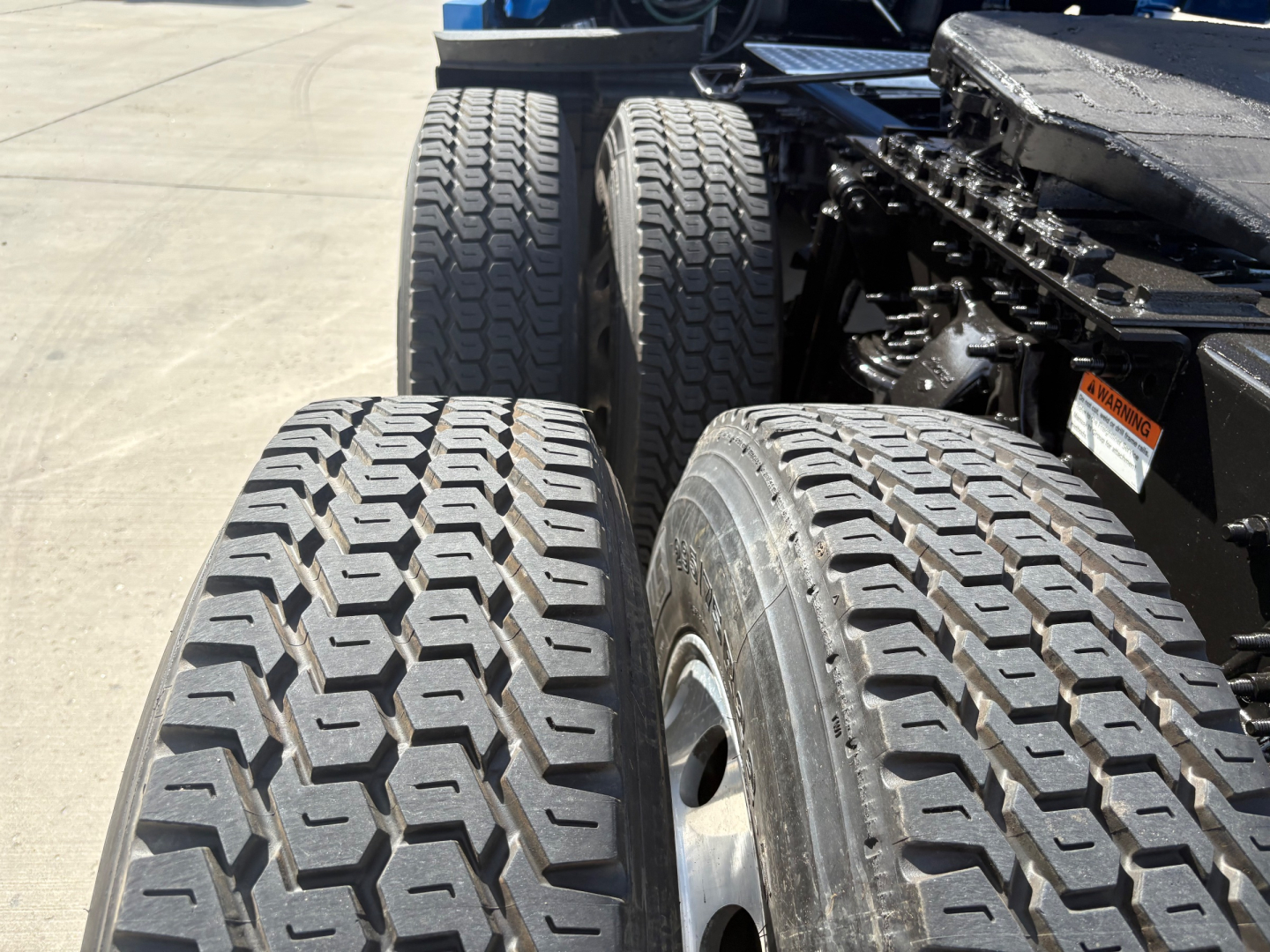 Trucks rear dual tires visible with tread pattern and wheel hubs; chassis and suspension components in view.