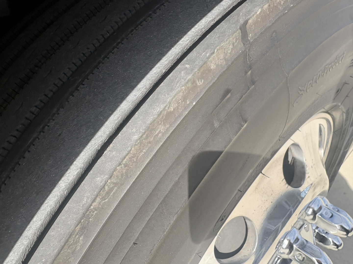 Tire and wheel close-up on Freightliner PT126064ST listing image; partial tread visible and wheel rim with lug nuts.