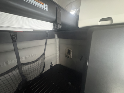 Conventional sleeper truck interior cargo area showing storage nets, side wall panel, and window area; no engine or fluid text visible.