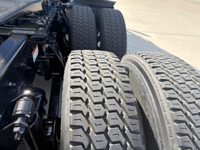 Freightliner truck rear tandem wheels and suspension showing dual tire tread pattern and drive axles.