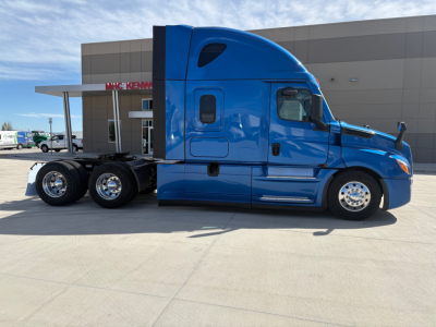 Truck side view of a blue Freightliner PT126064ST 6x4 tractor with sleeper cab, showing cab door, window, and rear wheels.