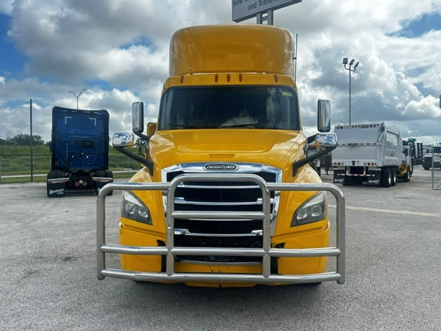 Front view of a yellow 2019 Freightliner Cascadia 126 daycab with a large chrome grille guard and tall sleeper.