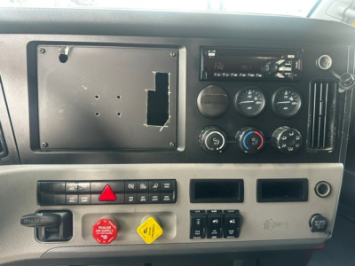 Dashboard panel of a 2019 Freightliner Cascadia 126 showngeometer gauges, control switches, and radio; blank mount plate on left where a display may be installed.
