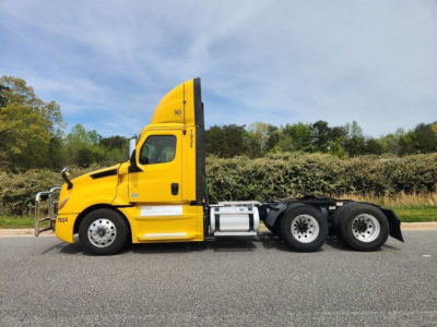 Yellow 2019 Freightliner Cascadia 126 conventional daycab tractor side view showing cab, fuel tanks, and rear axles with three tandem wheels.