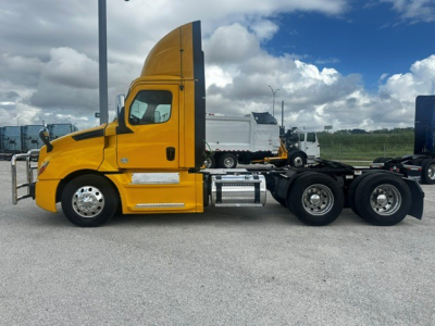 Truck cab with bright yellow Freightliner Cascadia 126, side view showing sleeper cab and chassis with dual rear axles.
