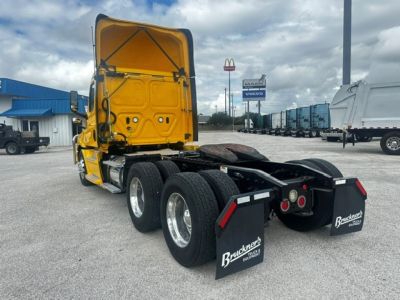 Tractor truck rear/side view showing tandem axle group and mud flaps with Bratco? branding, yellow cab, black chassis, 3-axle configuration, Freightliner Cascadia 126 emblem not visible.