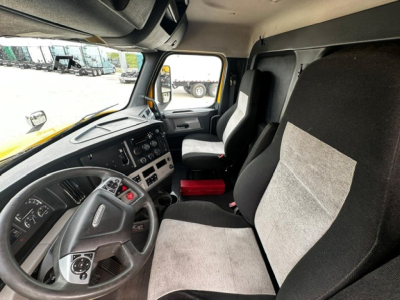 Truck cab interior of a 2019 Freightliner Cascadia 126, driver seat and passenger seat visible, dashboard with steering wheel and control panels.