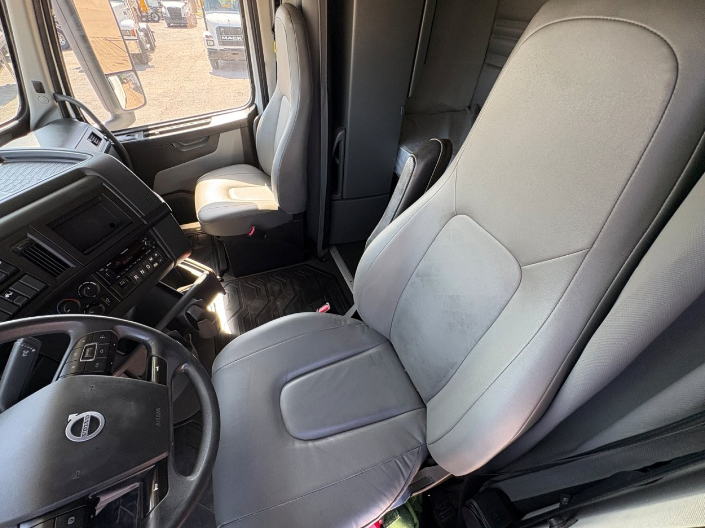 Volvo VNR64T660 truck cabin interior showing driver seat and passenger seat with dashboard controls and steering wheel.