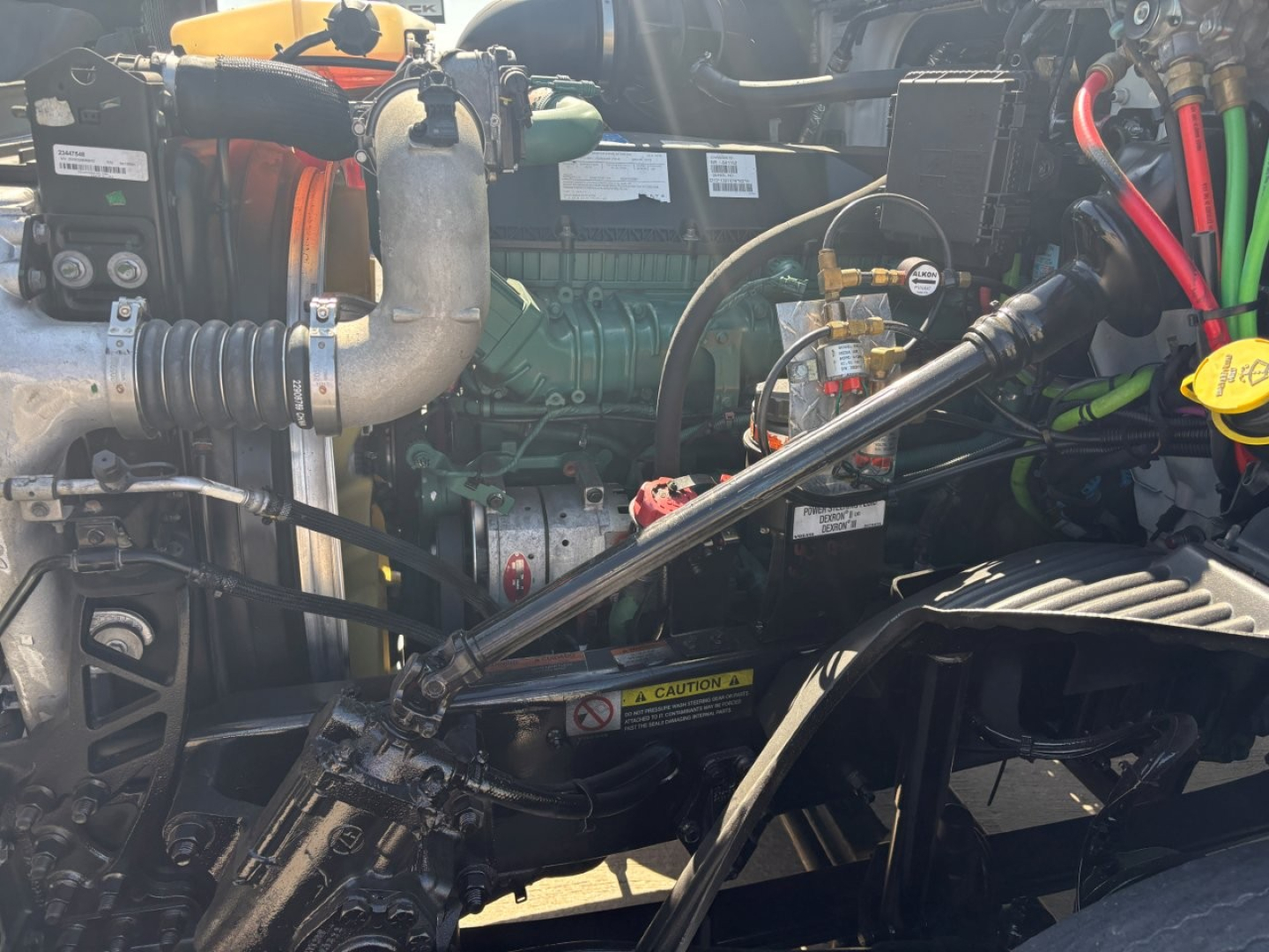 Volvo VNR engine bay with green diesel engine, hoses, and yellow dipstick visible.