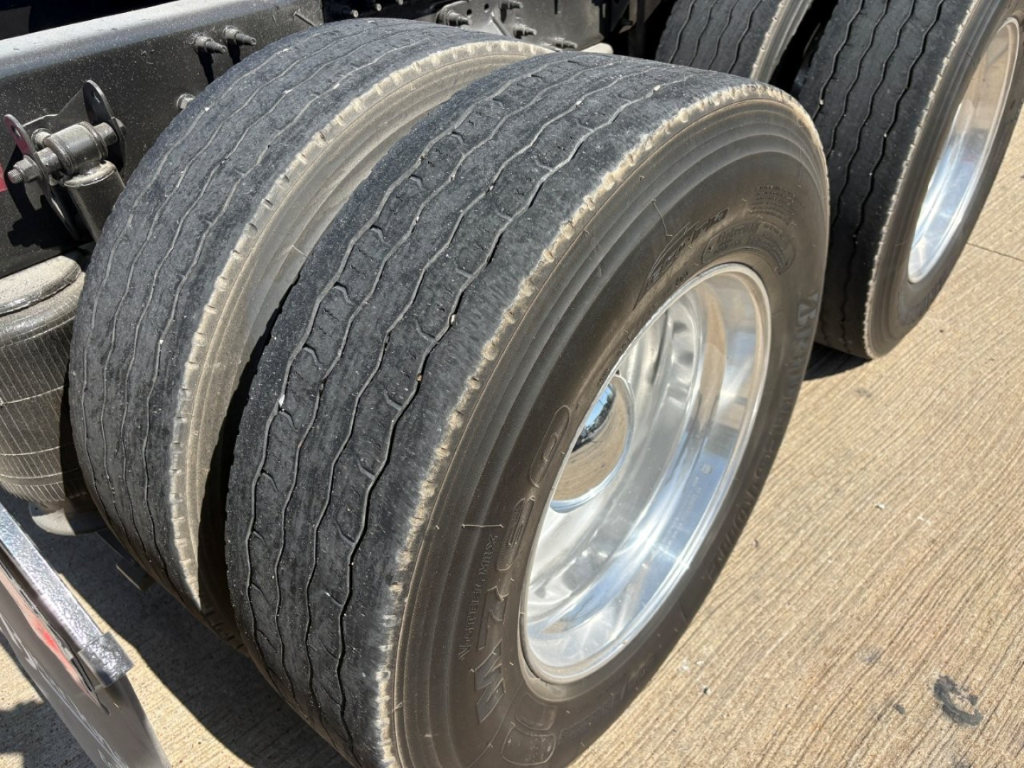 Volvo VNR64T660 truck rear dual tires with chrome rims; tread visible and air lines; part of rear axle area.