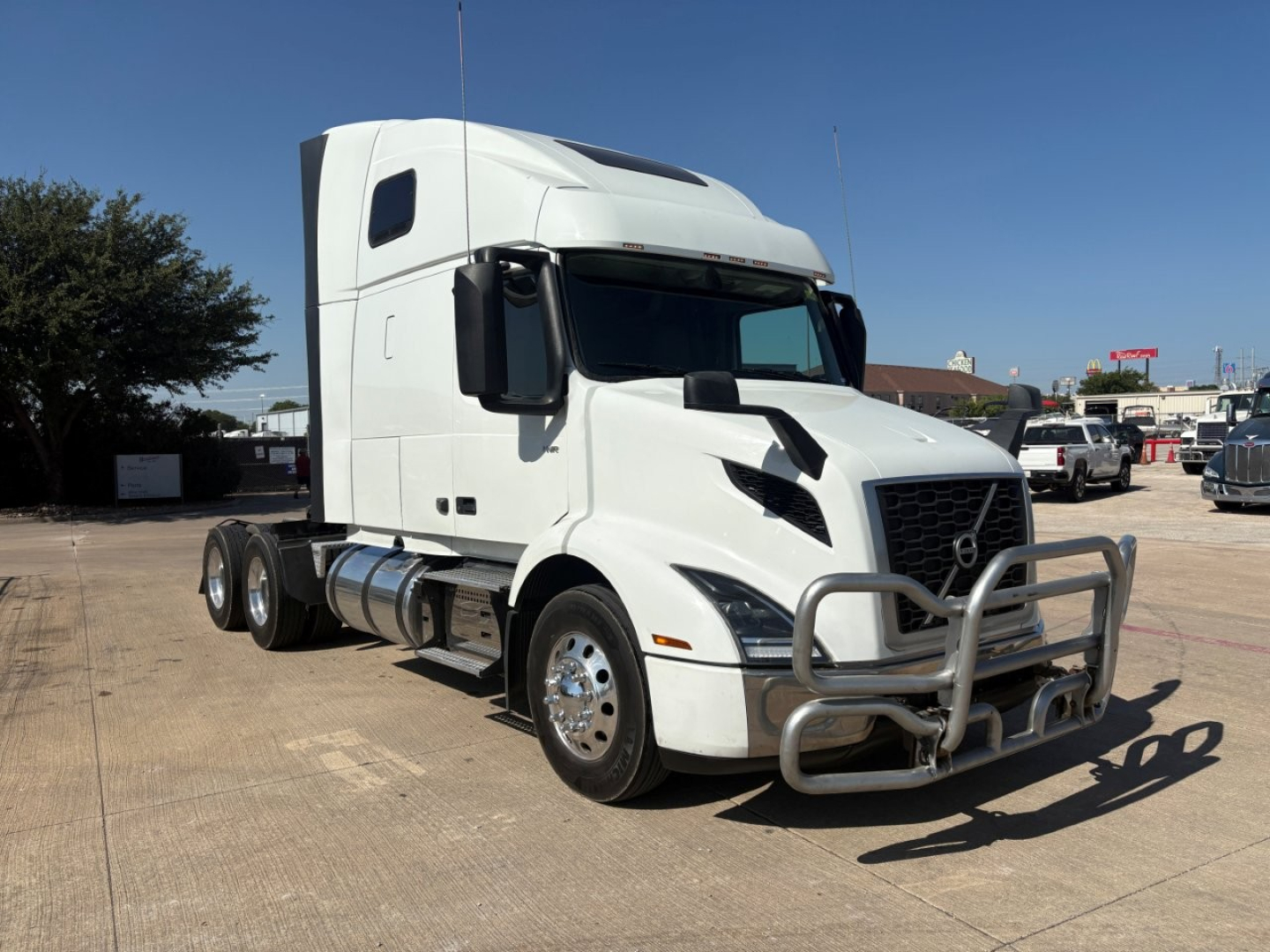 Volvo VNR64T660 conventional sleeper truck in white, front and side view showing large bull bar and aerodynamic cab.