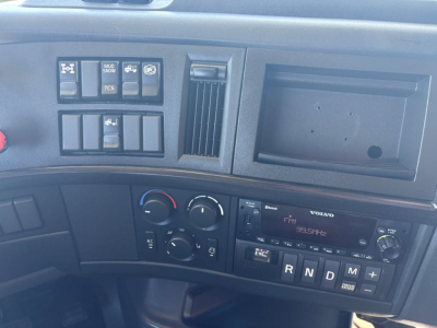Dashboard area of a Volvo VNR truck showing control switches, climate controls, radio, and gear selector with R N D M indicators.