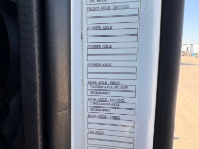 Truck door jamb data plate showing axle labels and tire/rear axle specifications on a Volvo VNR cab. Visible rows include FRONT AXLE - SECOND, PUSHER AXLE, REAR AXLE - FIRST, SECOND, THIRD with associated codes.