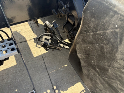 Volvo VNR truck chassis area showing hydraulic lines and exposed electrical connectors near the cab floor and drive line.