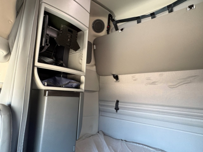 Volvo VNR64T660 sleeper cab interior showing storage compartments and sleeper bunk with light gray upholstery.