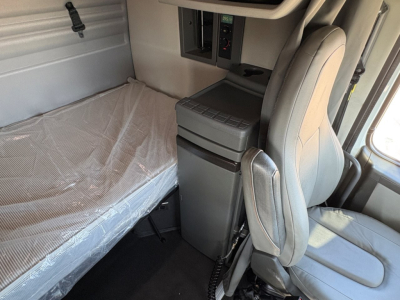 Volvo VNR64T660 truck sleeper cab interior showing bunk bed with plastic cover and driver seat, storage cabinet, and control panel visible