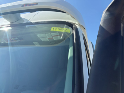 Truck cab window with yellow stock tag  B3827 visible in windshield, partial cab roof and side mirror, 2024 Volvo VNR64T660 listing.