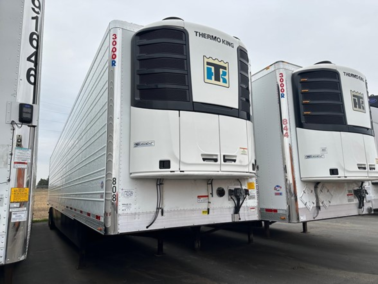 Utility 3000R trailer with Thermo King unit on front, white reefer trailer, two units visible in a lot, front facade shows cooling units and HT logo.