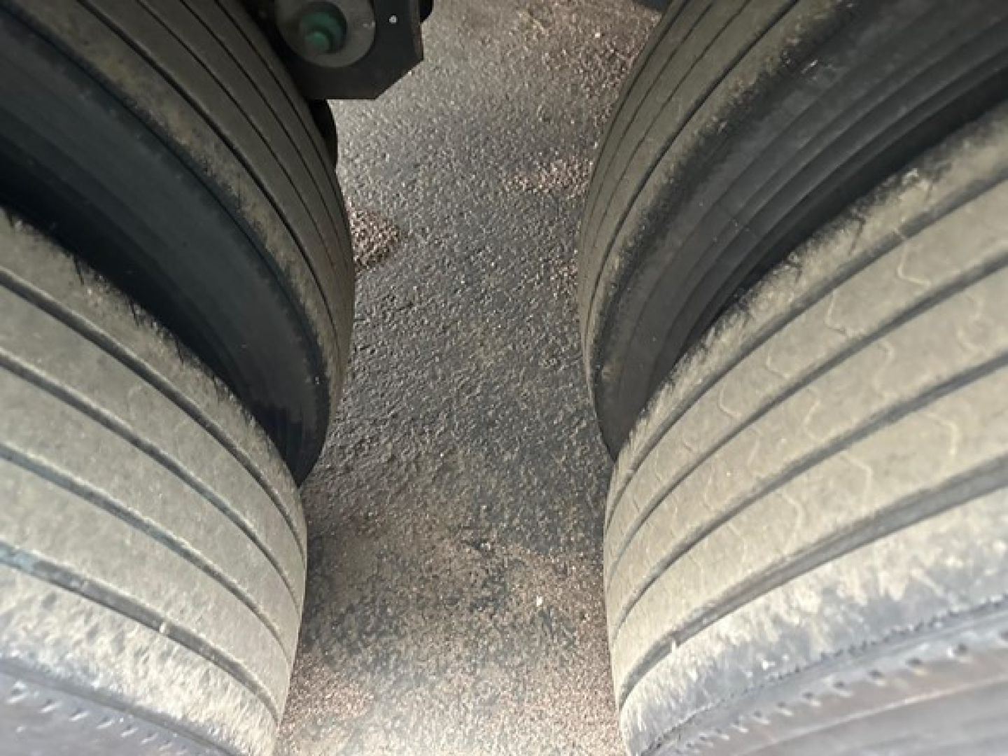 Two large trailer tires with treads visible, close-up view of wheel area