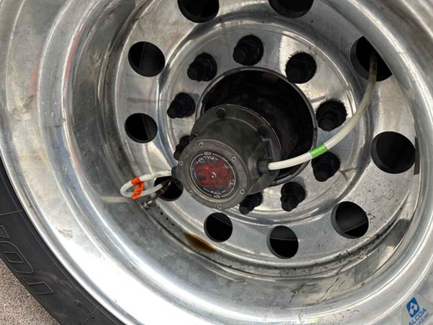 Wheel hub with steel rim showing circular vent holes and a central hub with electrical connector on a Utility 3000R trailer wheel.